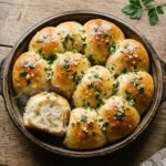 Golden pull-apart garlic butter bread rolls in a baking dish with parsley